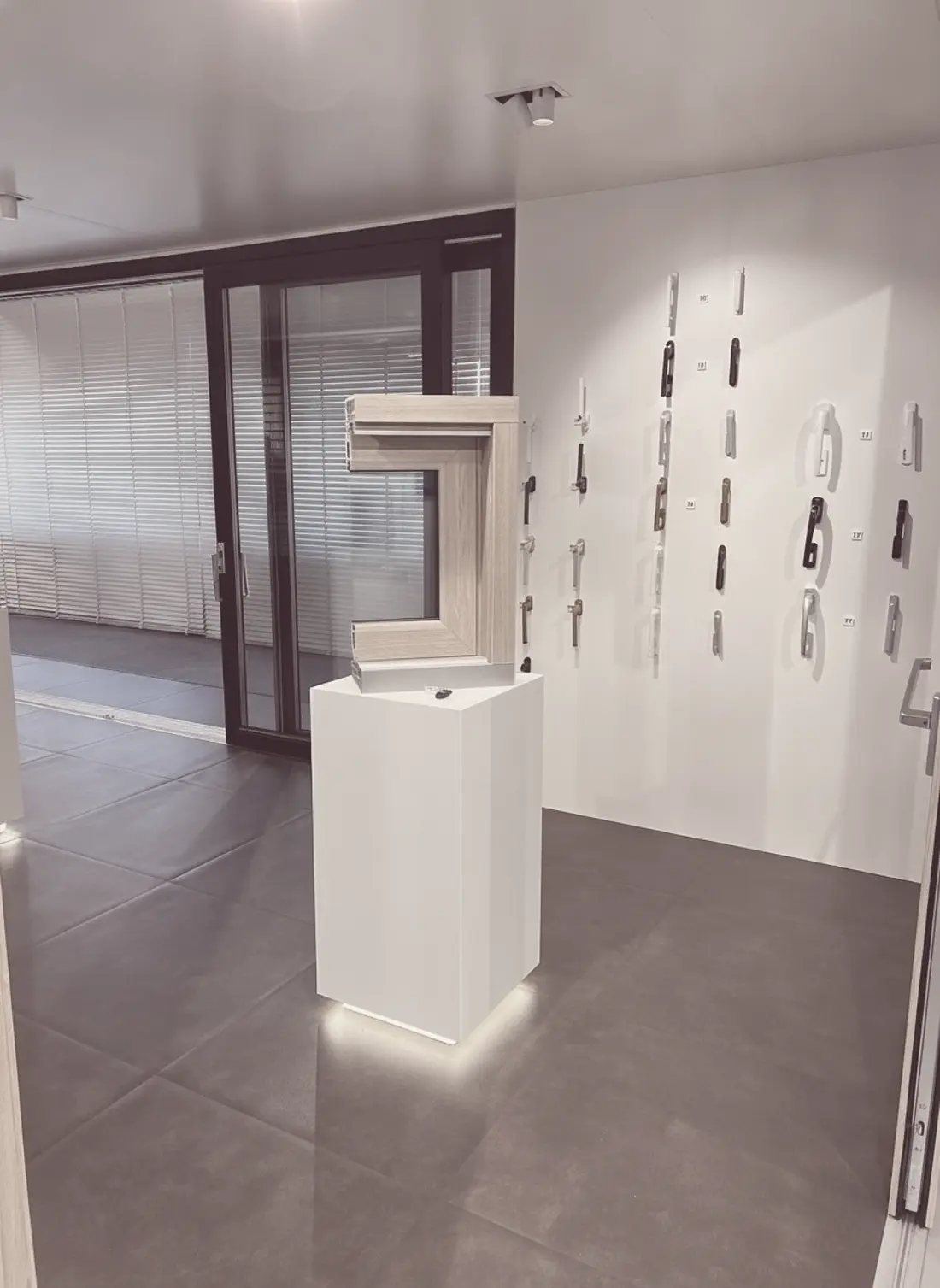 Profilmuster auf einem Podest, dahinter eine Wand mit Griffen und eine große Hebeschiebetür